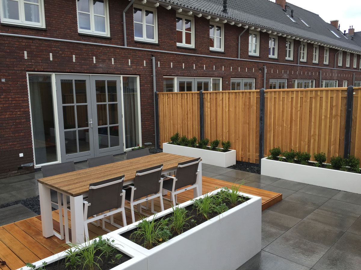 Binnentuin met vlonder en witte plantenbakken