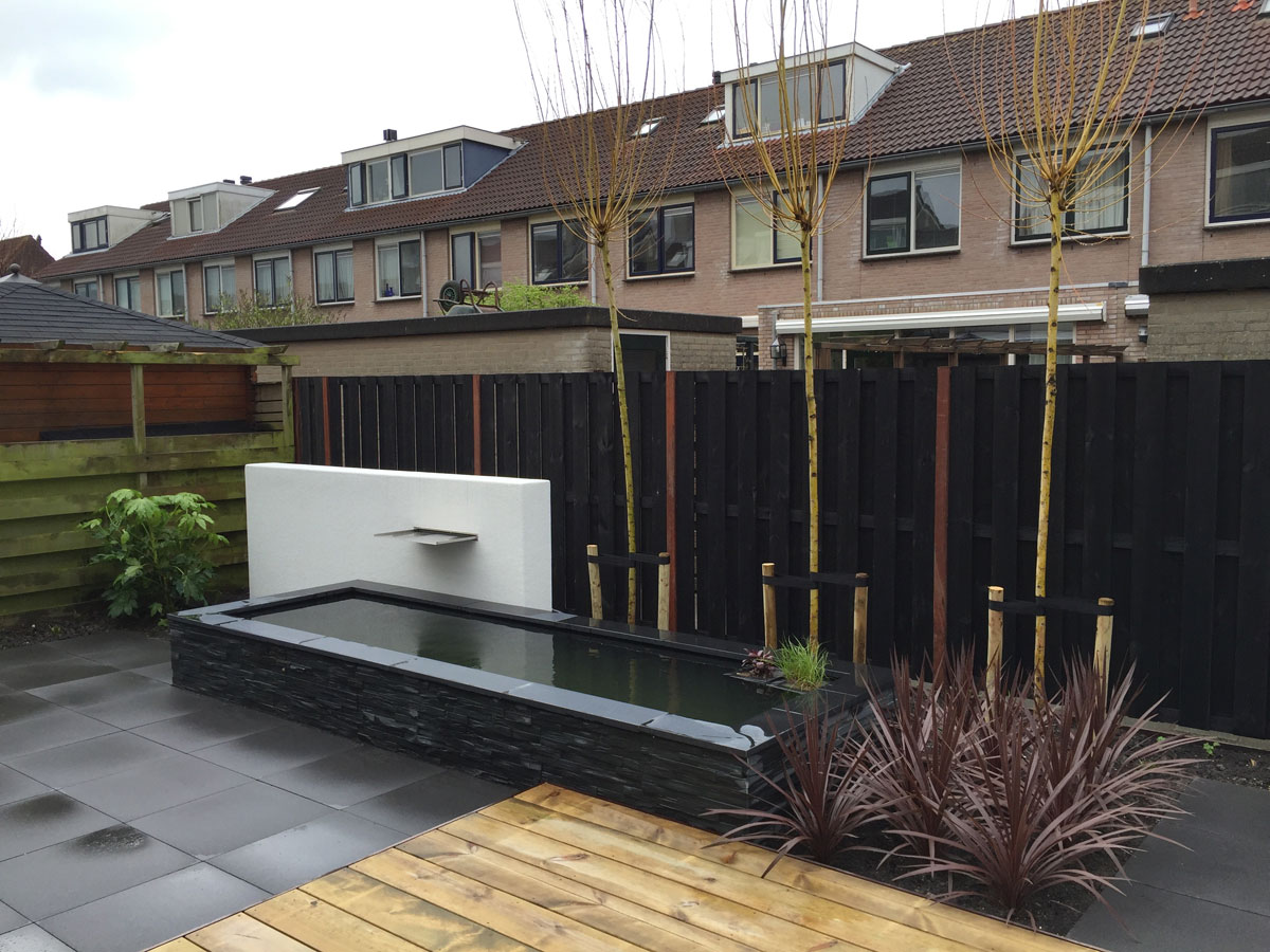 Witte muur met waterelement in een moderne tuin