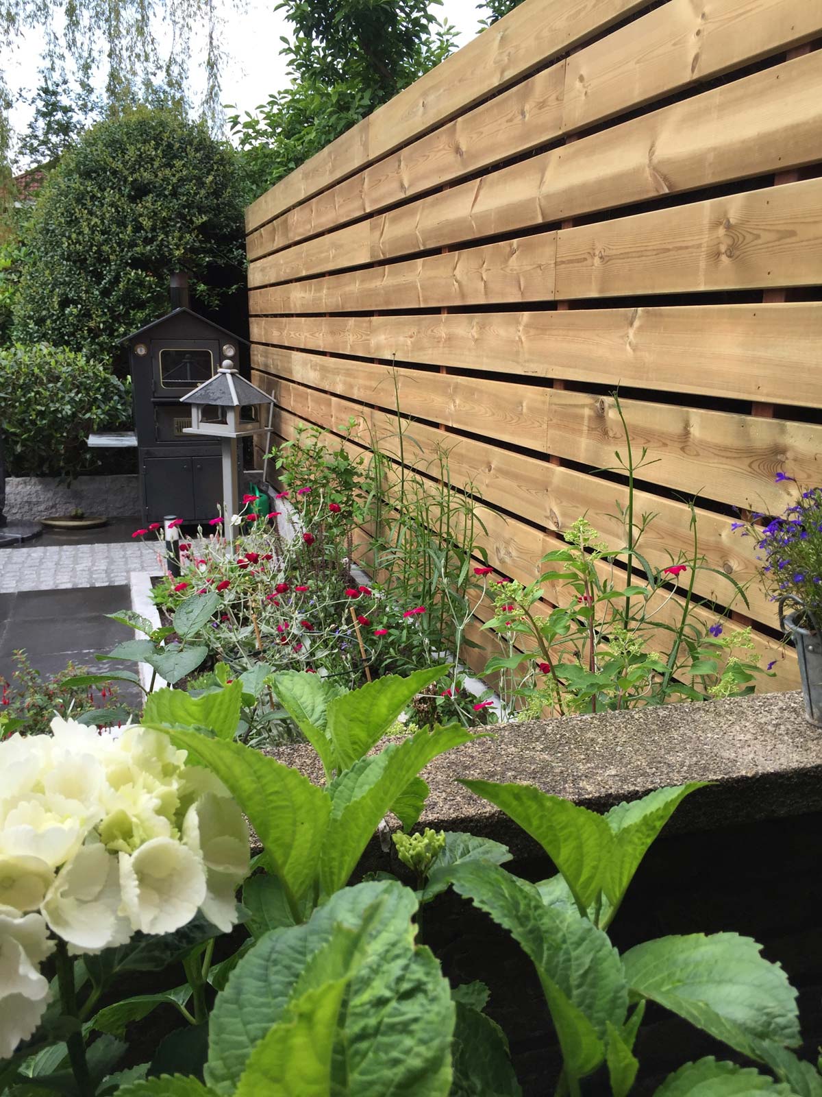 Horizontale schutting met bloeiende beplanting ervoor