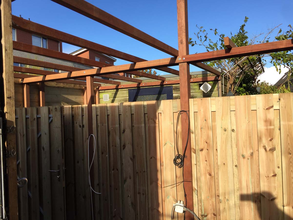 Hoek van een tuin met schutting en pergola