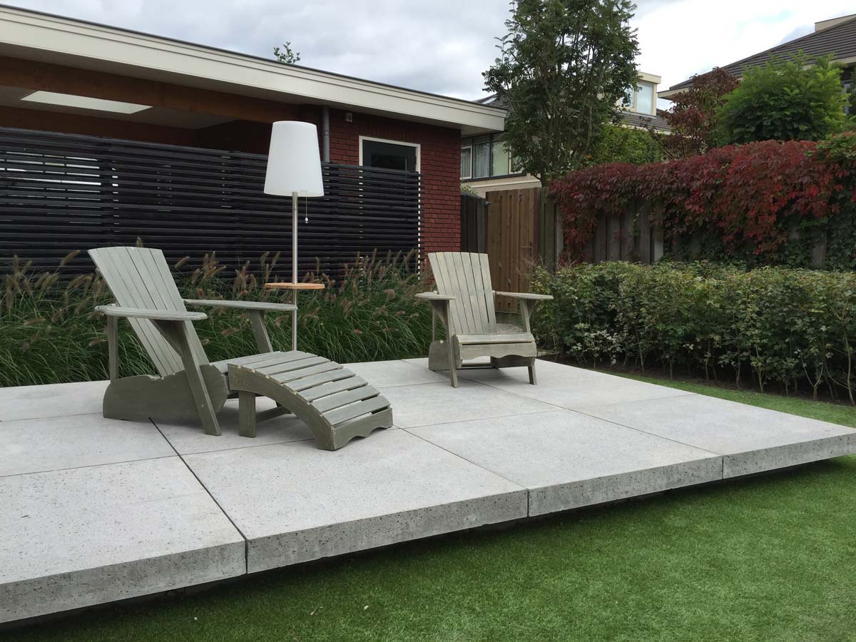 Tuin met haag, gazon en twee ligstoelen op het terras