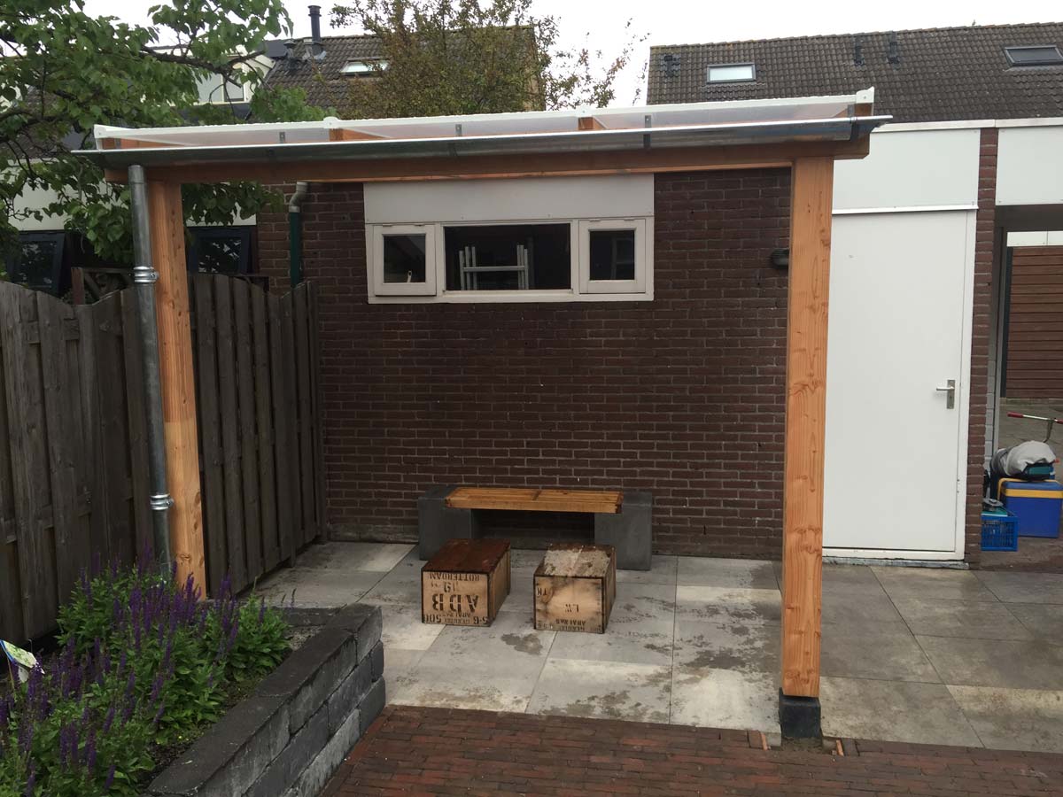 Overkapping tegen een berging met een houten tafel eronder