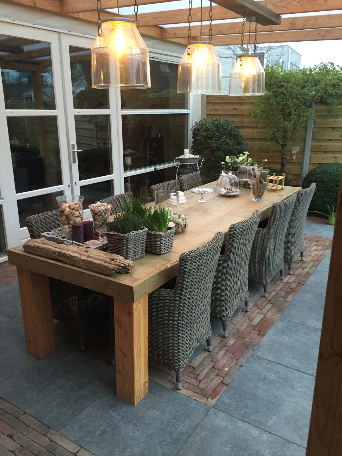 Overkapping met eettafel en hanglampen in de avond