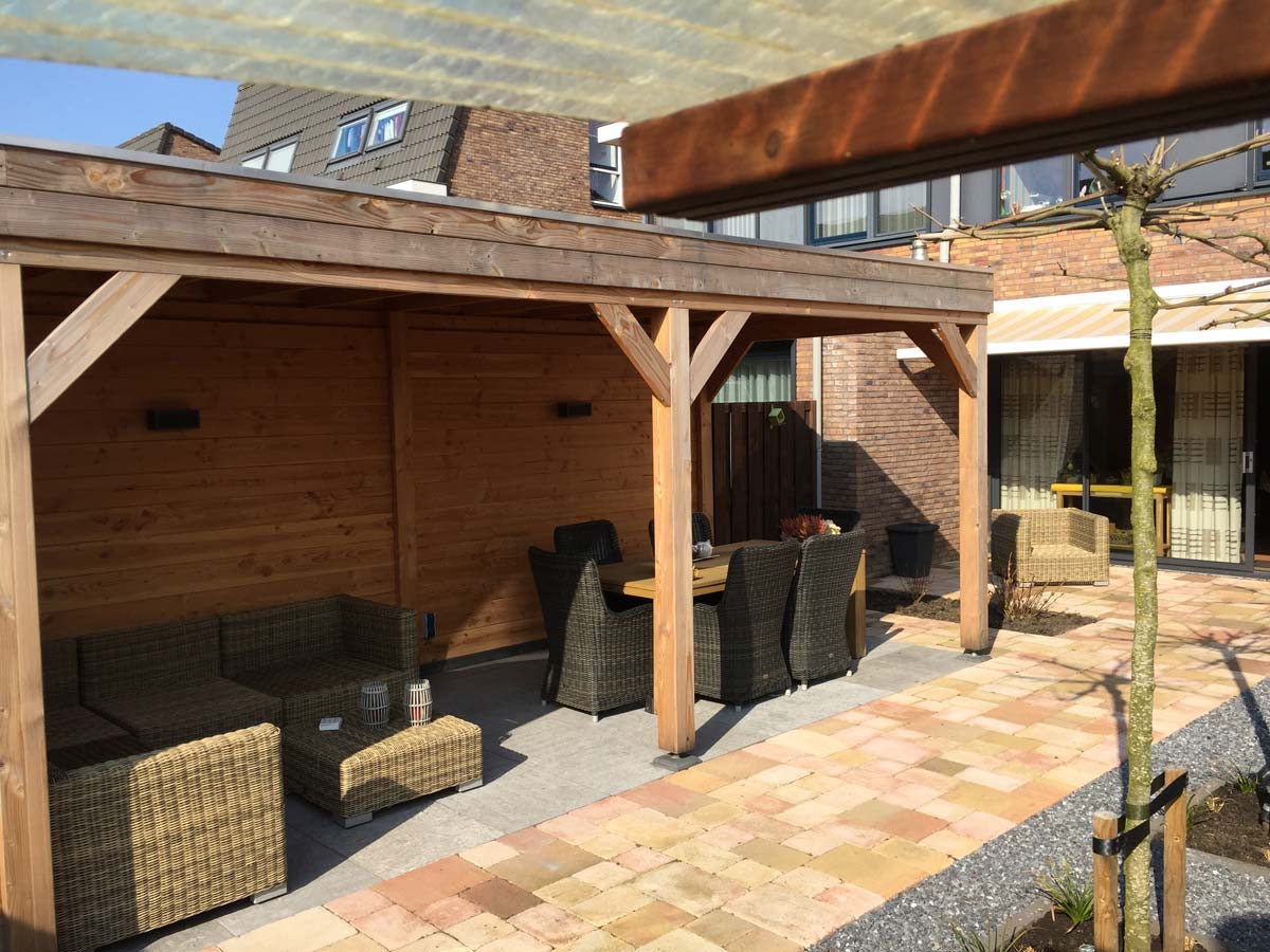 Tuin met gazon en een overkapping langs de woning