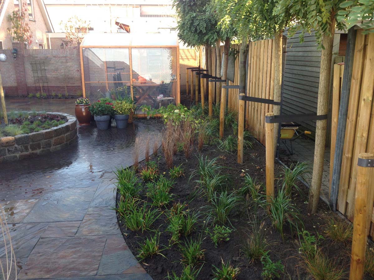 Tuin met natuurstenen verharding en een gebogen border