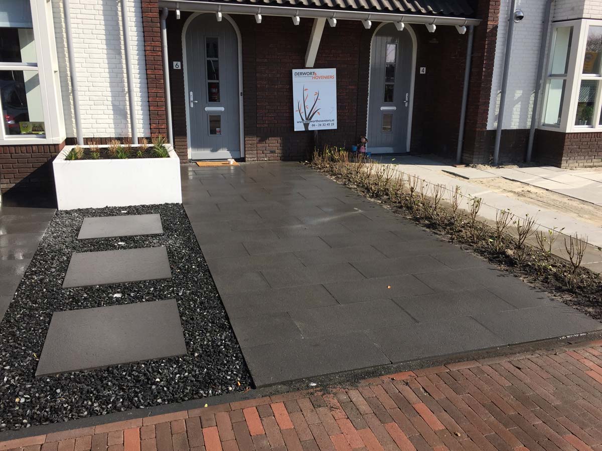 Voortuin met tegels, stapstenen en een plantenbak